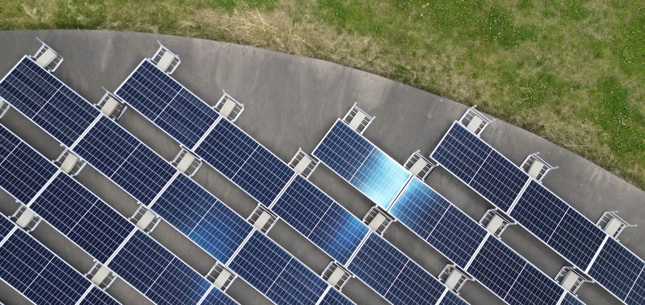 Top-down view of solar panels arranged on a green field, highlighting renewable energy.