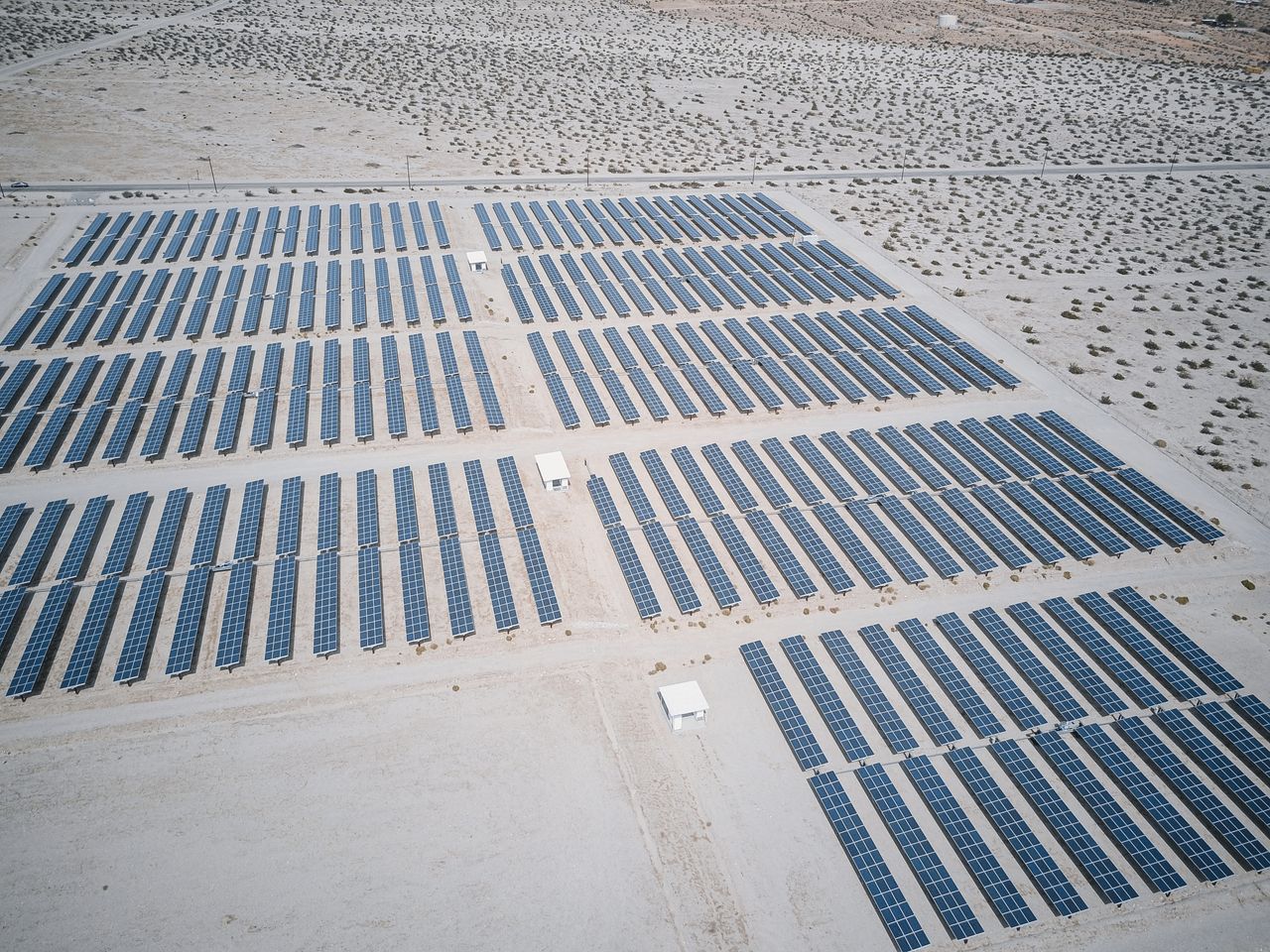 Expansive aerial view of solar panels in a desert, showcasing renewable energy technology.