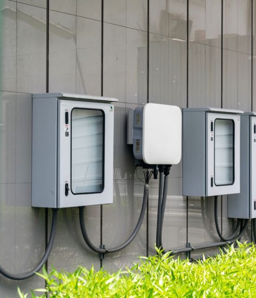 Close-up of outdoor electrical utility boxes with cabling on a building exterior.